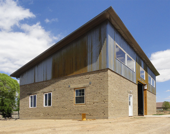 Passive solar commercial building utilizing exposed compressed soil blocks on exterior and interior